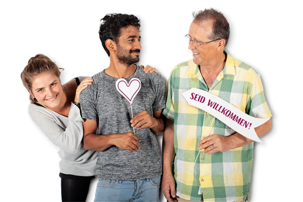 Zwei M&auml;nner unterhalten sich, eine junge Frau schaut grinsend hinter einem von beiden vor