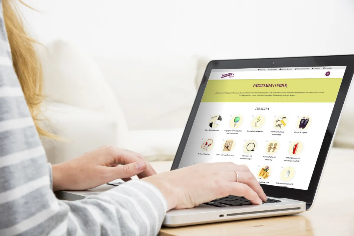 Eine Frau sitzt schreibend am Laptop und schaut auf eine Website