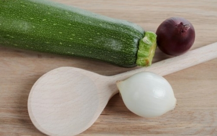 Kochl&ouml;ffel, Zwiebeln und Zucchini auf einem Tisch