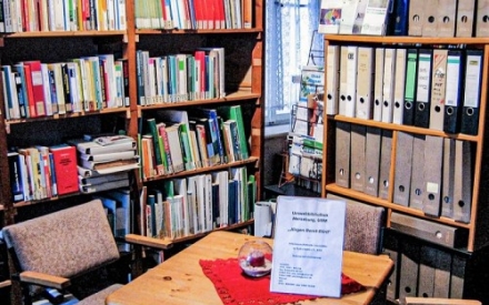 Der Bibiotheksraum mit B&uuml;cherregalen und einem Tisch.