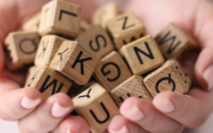 Zwei H&auml;nde sind zu einer Art Schale geformt, in der ganz viele Buchstabenw&uuml;rfel aus Holz liegen