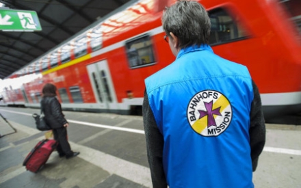 Ehrenamtlicher schaut zu einem ankommenden Zug