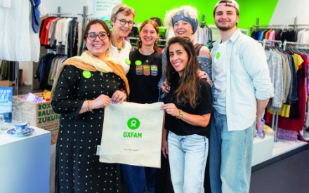 Eine Gruppe von Ehrenamtlichen steht in einem Oxfam-Shop. Alle tragen leuchtendgr&uuml;ne Buttons, die Sie als Mitglieder des Teams auszeichnen und l&auml;cheln in die Kamera.