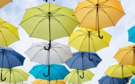 ein Ausschnitt des Himmels mit vielen Regenschirmen in Blau, Gelb und Wei&szlig;, die zu schweben scheinen