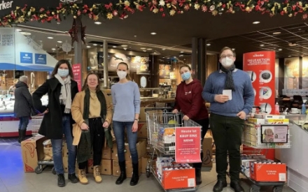 F&uuml;nf junge Menschen stehen in einem Einkaufscenter und f&uuml;hren eine Spendenaktion durch. Zwischen Ihnen stehen zwei gro&szlig;e Einkaufswagen.