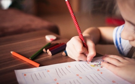 M&auml;dchen, dass mit Bleistift auf ein Blatt schreibt und malt