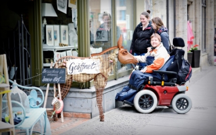 Frau im Rollstuhl vor einem Gesch&auml;ft
