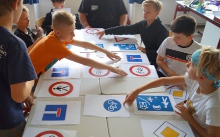 eine Gruppe Jugendlicher sitzte an einem Tisch und beugt sich &uuml;ber Bilder von Verkehrszeichen