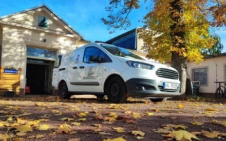 Ein wei&szlig;er Lieferwagen vom Tierschutzhalle steht vorm Haupthaus des Vereins. Im Hintergrund ist ein Baum mit herbstbunt gef&auml;rbten Bl&auml;ttern zu sehen.