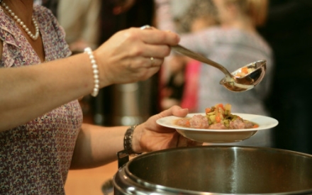 Person gibt Suppe auf einen Teller
