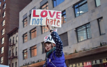 Eine Jugendliche mit dem Schild "Love not hate" auf einer Demonstration