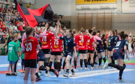 Junge Handball-Spielerinnen in Sportkleidung laufen auf dem Spielfeld aneinander vorbei und klatschen sich mit den H&auml;nden ab.