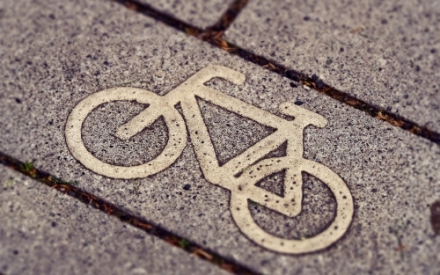 Ein kleines Fahrrad aus Metall, dass in einen Pflasterstein eingelassen ist.