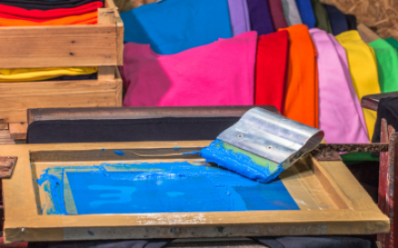 Siebdrucktisch mit Sieb und Rakel und blauer Farbe
