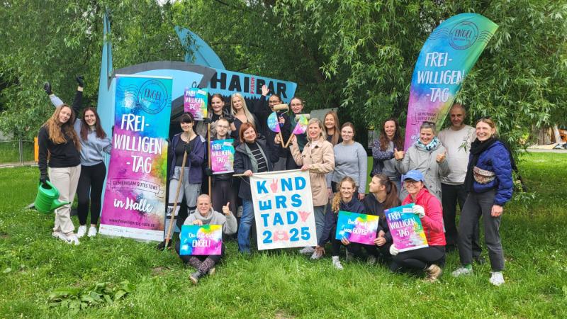 Menschen stehen im Grünen mit Plakaten und Rollups zum Freiwilligentag