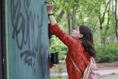 eine junge Frau malt eine dunkelgrüne Wand an 