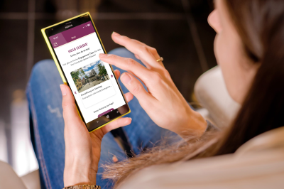 Eine Frau schaut aufs Smartphone, auf dem Handybildschirm ist die Engagement-App zu erkennen