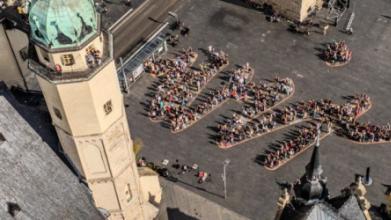 Das Logo des WIR-Festivals wird von Menschen auf dem Marktplatz von Halle nachgestellt. Auf dem Boden wurde ein riesiges WIR geschrieben, die Menschen haben sich so aufgestellt, dass die den Schriftzug nachbilden.