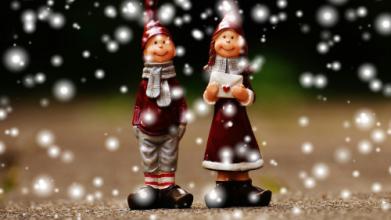 Zwei Wichtelfiguren aus Keramik stehen im Schneegestöber. Die Wichtelin hält einen Brief mit einem Herz drauf in der Hand.