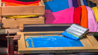 Siebdrucktisch mit Sieb und Rakel und blauer Farbe
